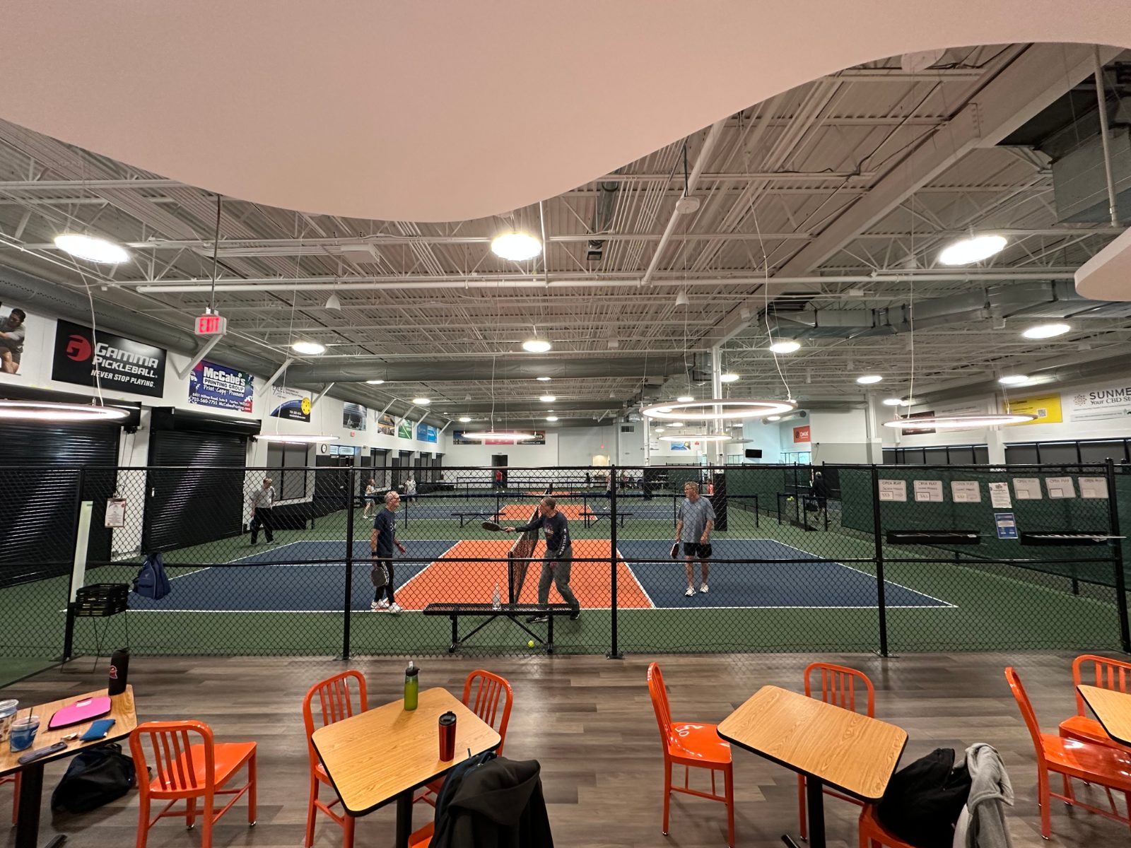 Cafe seating looks straight onto the courts — somewhere to sit out a round or wait for a game.
